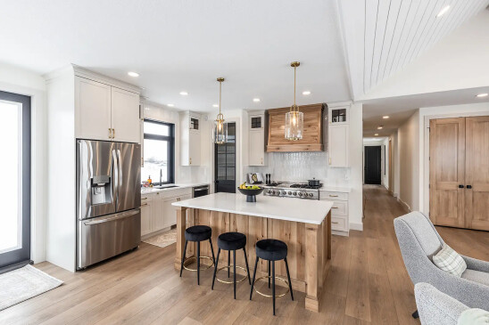Custom RTM home kitchen with wood range hood, stainless steel appliances and large island seating in Alberta and Saskatchewan