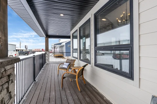 Covered front porch of RTM home with composite decking, black railing and outdoor seating in Alberta and Saskatchewan