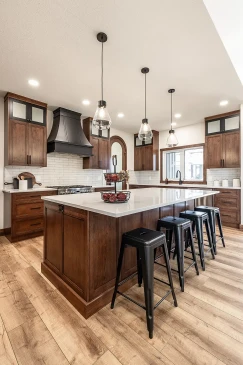 Modern kitchen with large island, wood cabinetry, stainless steel appliances, pendant lights, and bar seating in an open-concept RTM home.
