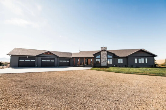 Custom luxury home with attached triple garage, stone chimney, and modern craftsman exterior.