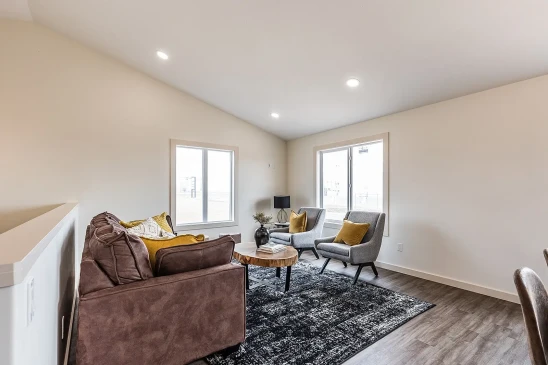 Cozy living room in RTM home with leather sofa, accent chairs and large windows in Alberta and Saskatchewan