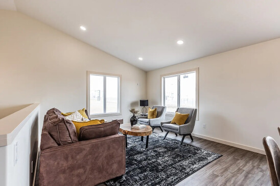 Cozy living room in RTM home with leather sofa, accent chairs and large windows in Alberta and Saskatchewan