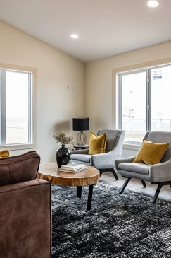 Modern RTM home living space with gray accent chairs, wood coffee table and recessed lighting in Alberta and Saskatchewan