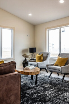 Modern RTM home living space with gray accent chairs, wood coffee table and recessed lighting in Alberta and Saskatchewan