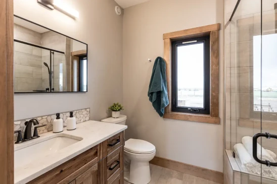 Modern bathroom in RTM home with walk-in glass shower and custom wood vanity, ready-to-move home interior in Alberta and Saskatchewan