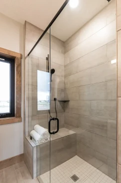 Modern walk-in glass shower with tiled walls and built-in bench in RTM home bathroom in Alberta and Saskatchewan