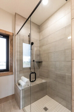 Modern walk-in glass shower with tiled walls and built-in bench in RTM home bathroom in Alberta and Saskatchewan