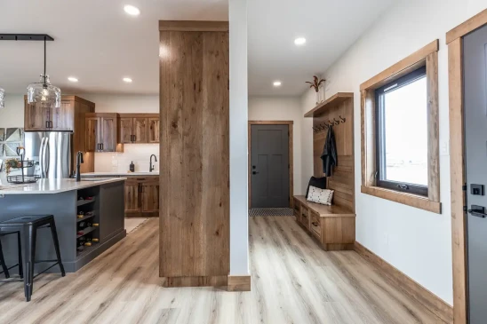 Spacious RTM home hallway with wood trim, durable vinyl plank flooring and open kitchen layout in Alberta and Saskatchewan