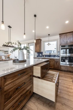 Custom RTM home kitchen island with quartz countertop, pendant lighting, and built-in wood drawers designed for organized storage.